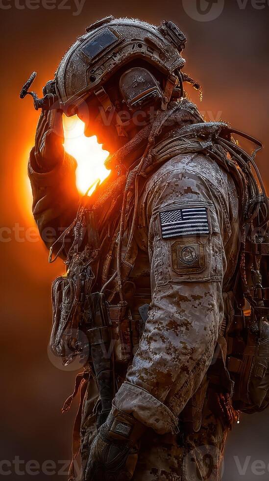 Soldier standing at sunrise saluting while wearing tactical gear in a desert landscape photo