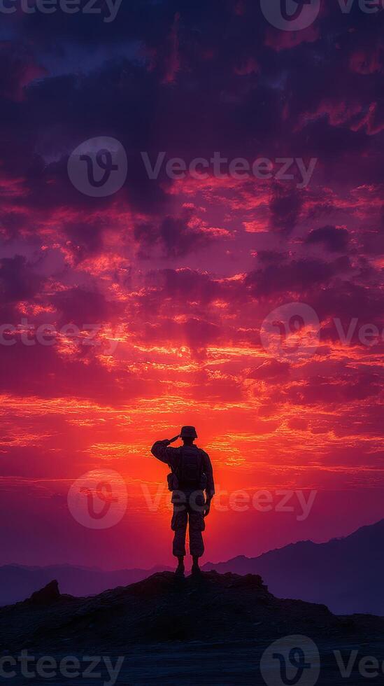 Soldier saluting at sunset in the mountains with colorful skies and dramatic clouds photo