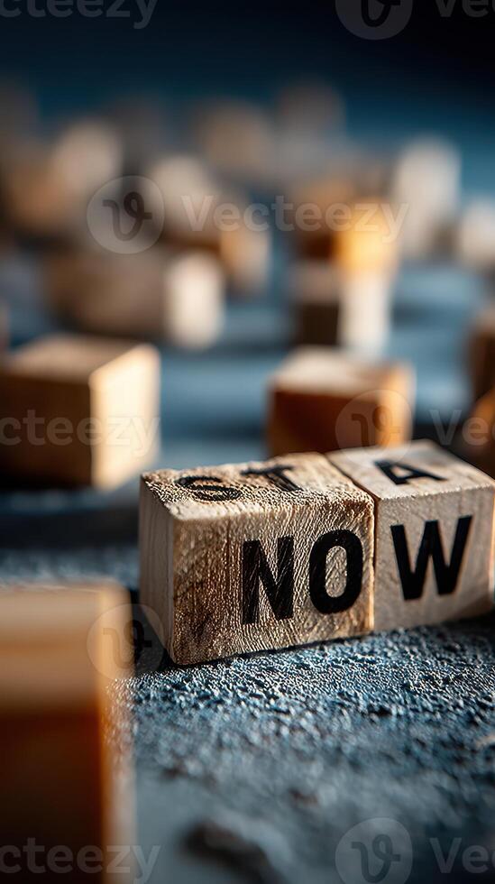 Focus on wooden blocks with letters spelling 'NOW' and scattered blocks in a creative arrangement on a textured surface photo