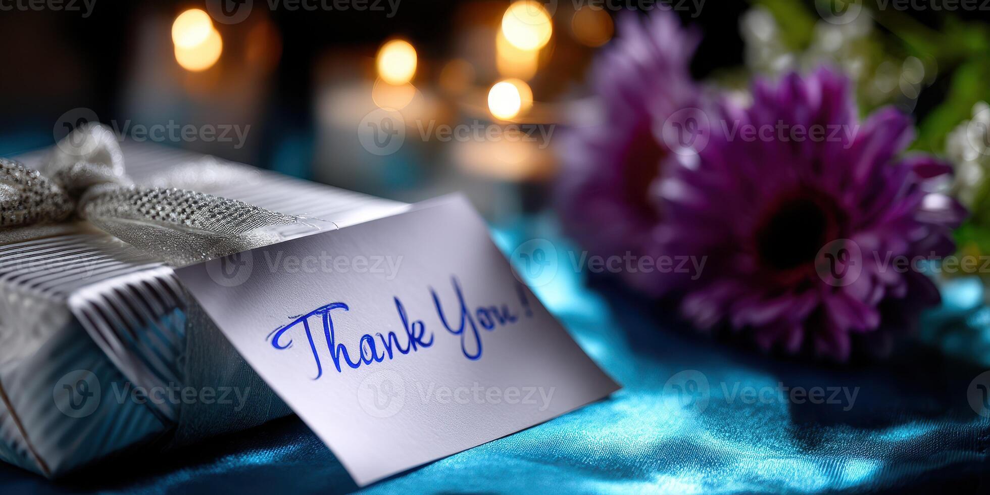 Gift with a thank you note beside purple flowers and candles on a blue surface during an evening gathering photo
