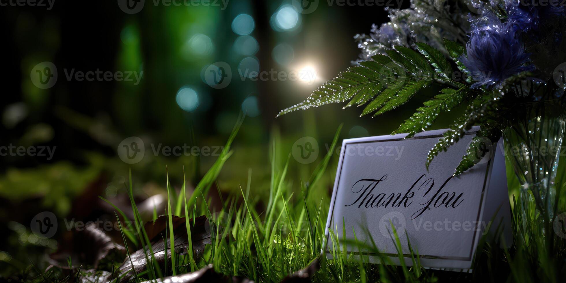 Thank you card placed among green grass and flowers in a serene forest setting at twilight photo
