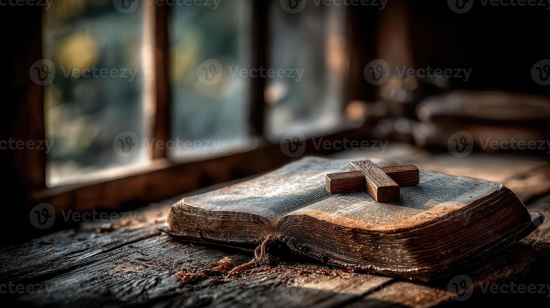 Old Bible resting on a wooden table with a cross in a dimly lit room during the early morning photo