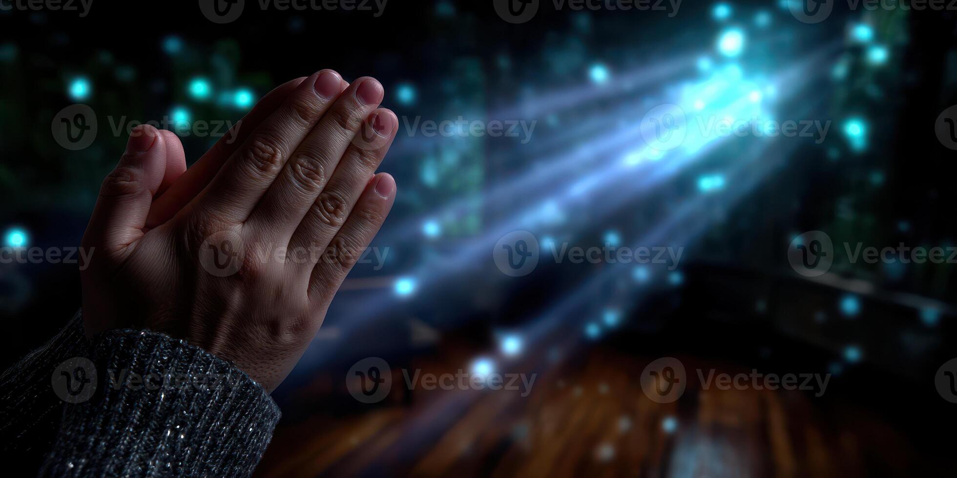 Hands together in prayer with soft light effects illuminating a serene space at night photo
