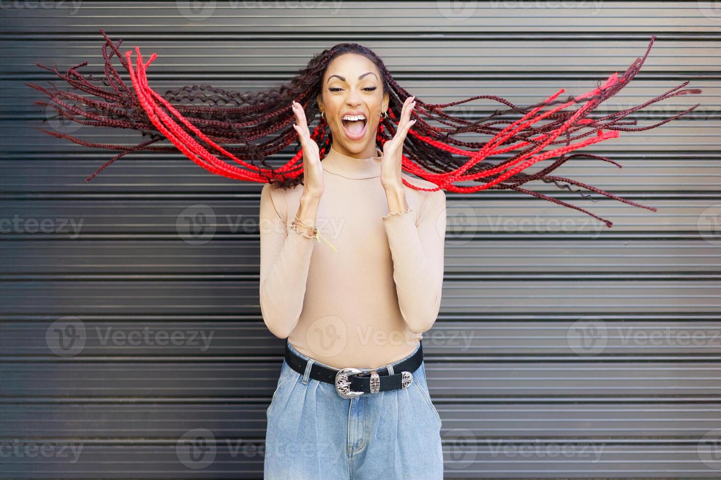 A Joyful Woman With Vibrant RedHighlighted Braids Posed Against a Textured Background photo