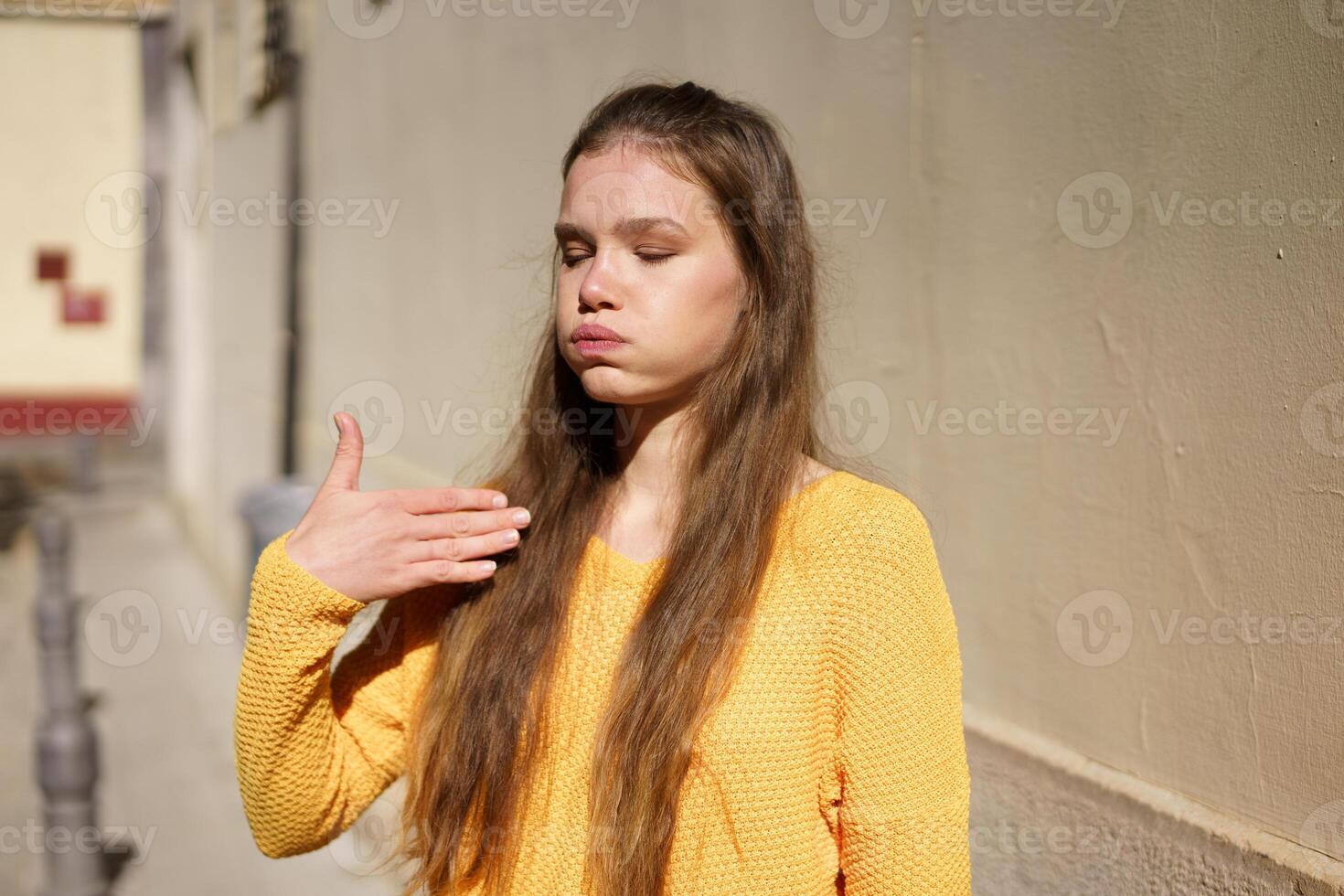 A Thoughtful Young Woman Dressed in a Vibrant Yellow Sweater Posing Gracefully Outdoors photo