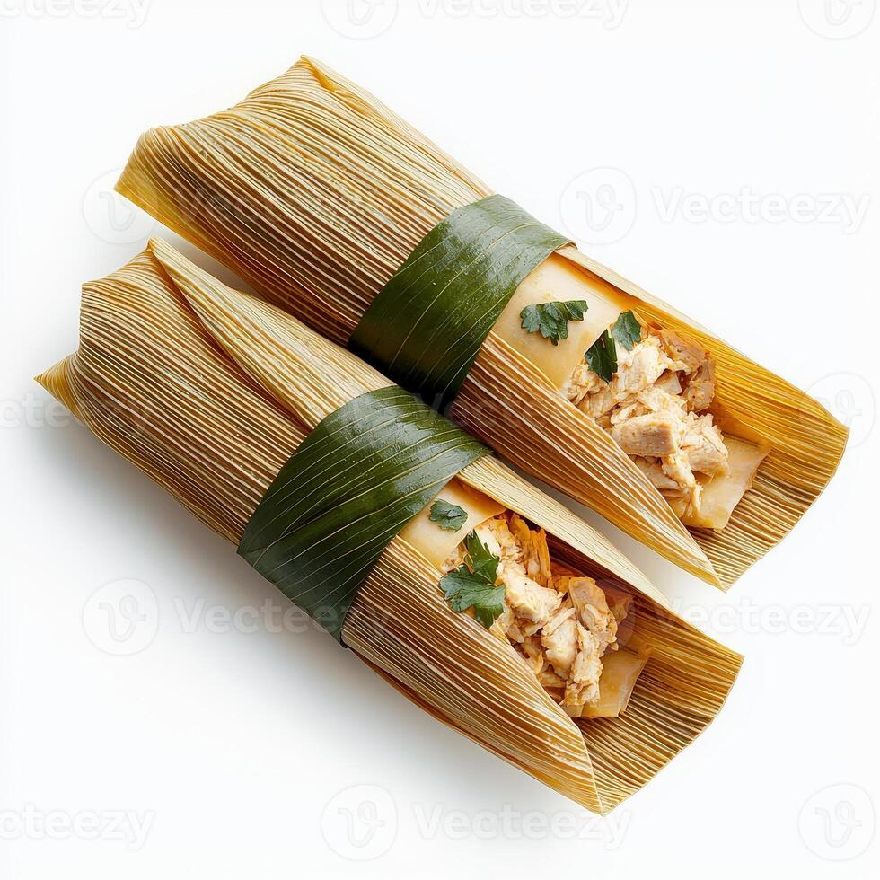 Two tamales wrapped in green leaves on a white surface photo