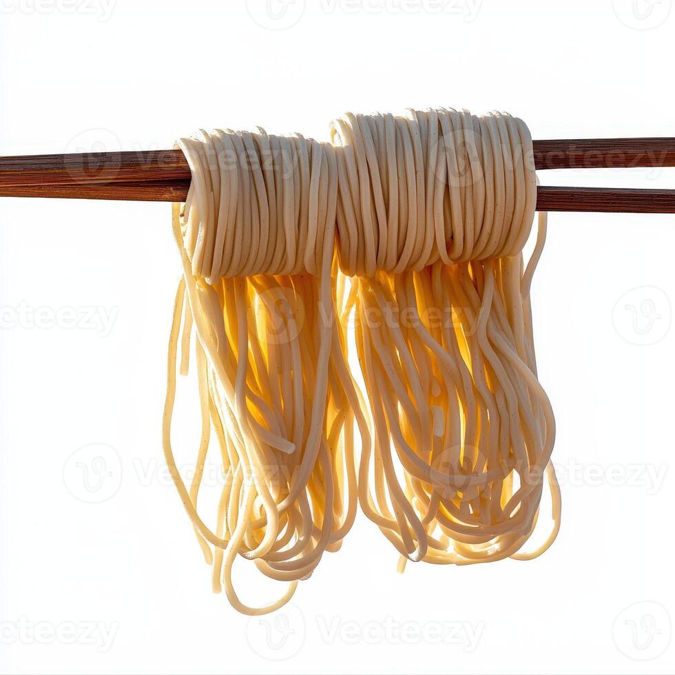 A pair of chopsticks with noodles hanging from them photo