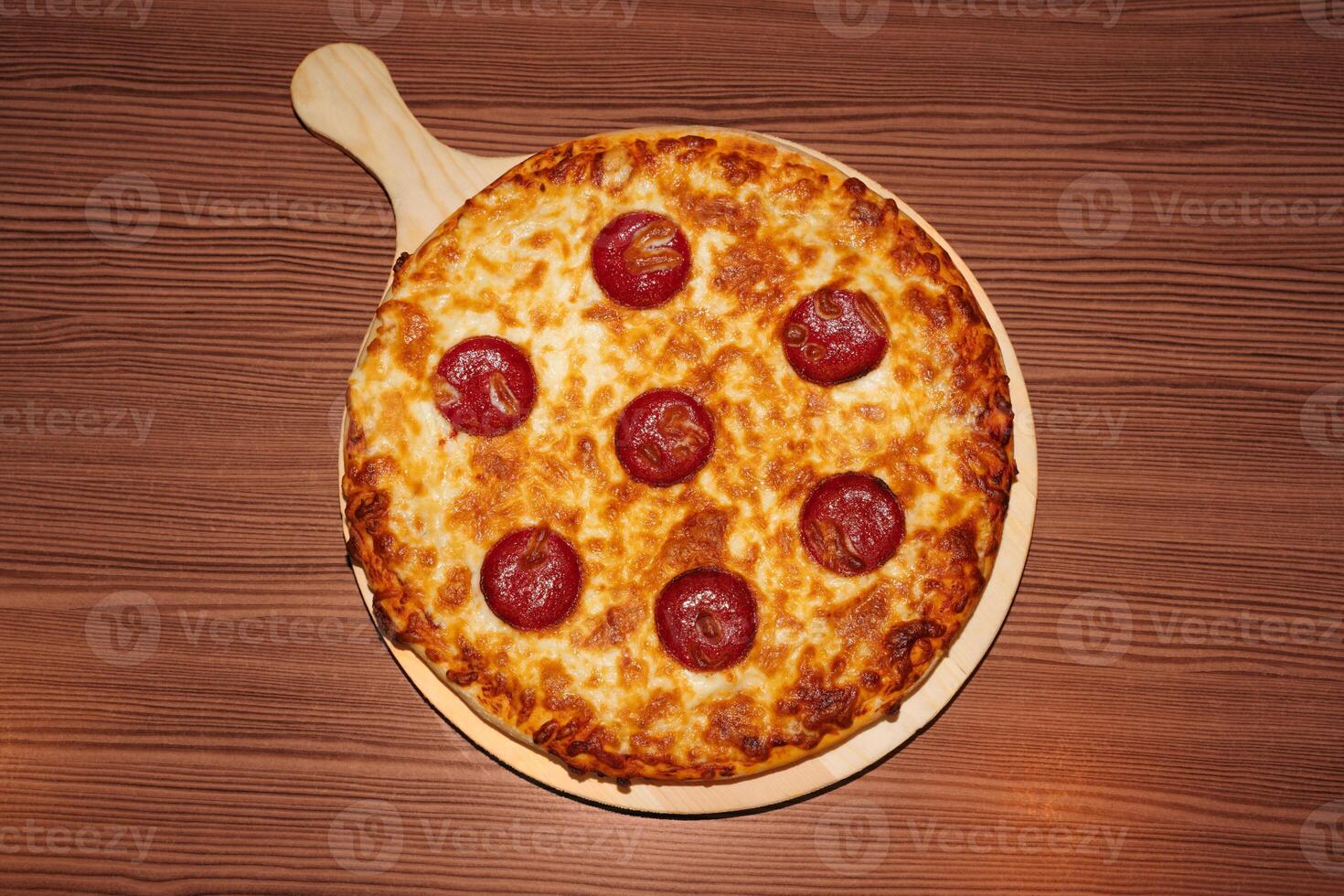 Pepperoni cheese pizza on wooden background. Retro flash food photography photo
