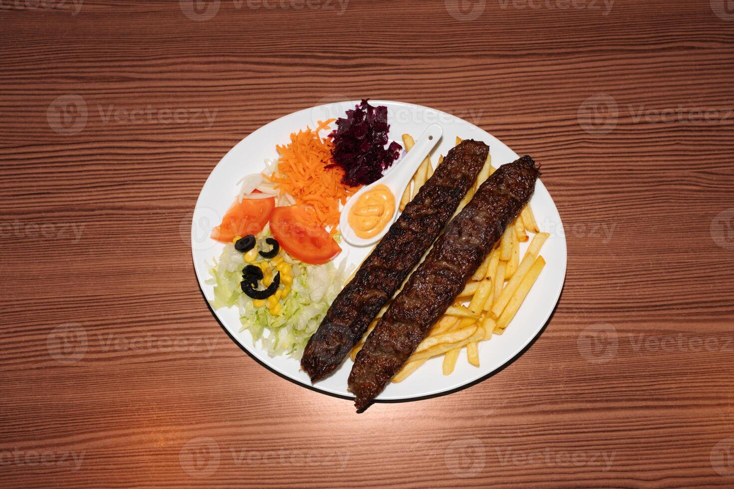Turkish kebab plate with fries, vegetables and sausages. Delicious freshly prepared meal, perfect for menus, restaurants, or food delivery concepts. photo