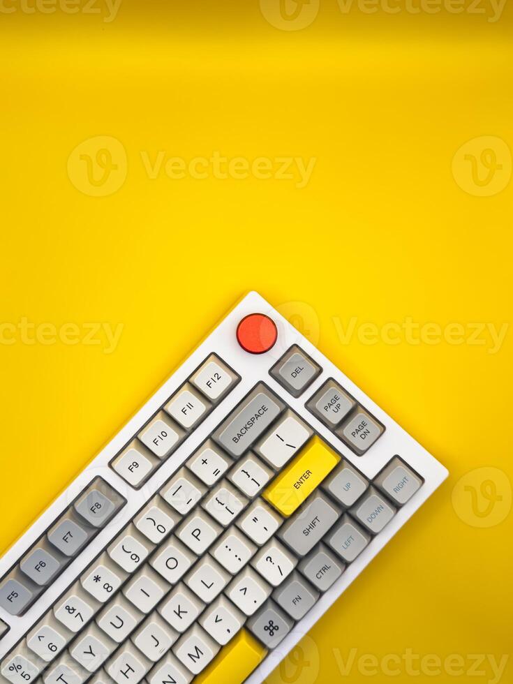 White keyboard on yellow background with bright red and yellow keys. Flat lay. Top view, copy space. ad. Vertical photo. photo