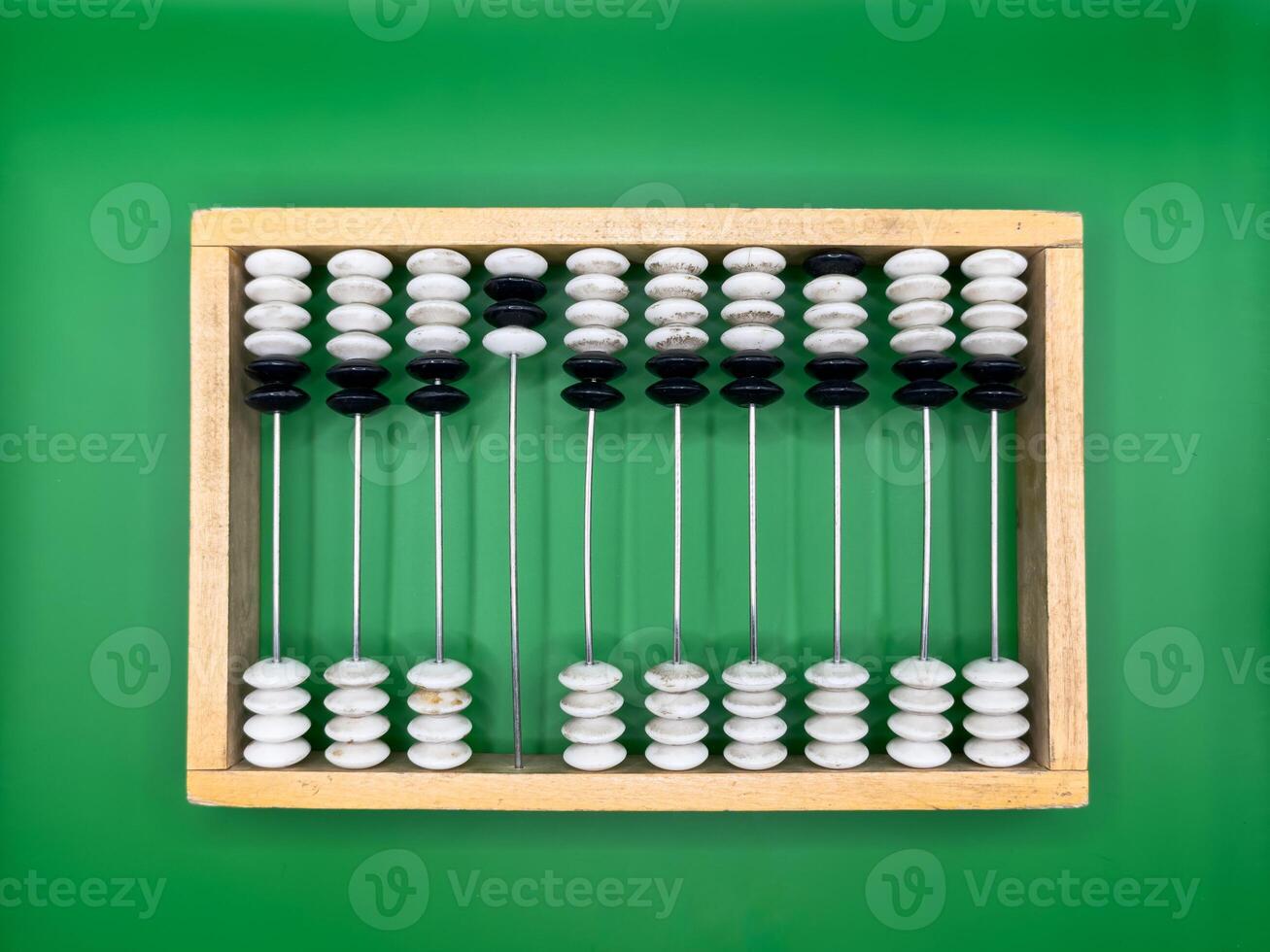 Russian old wooden abacus made of black and white pebbles and beige frame on dark green background in the center top view photo