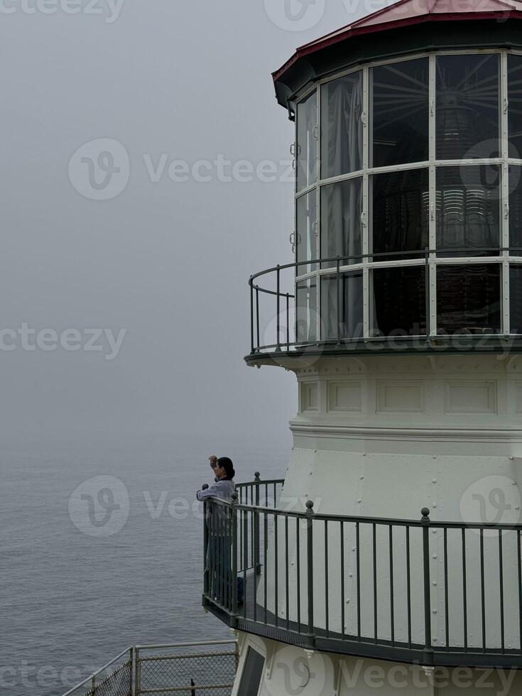 Girl on a lighthouse looking into the distance in foggy weather, vertical photo