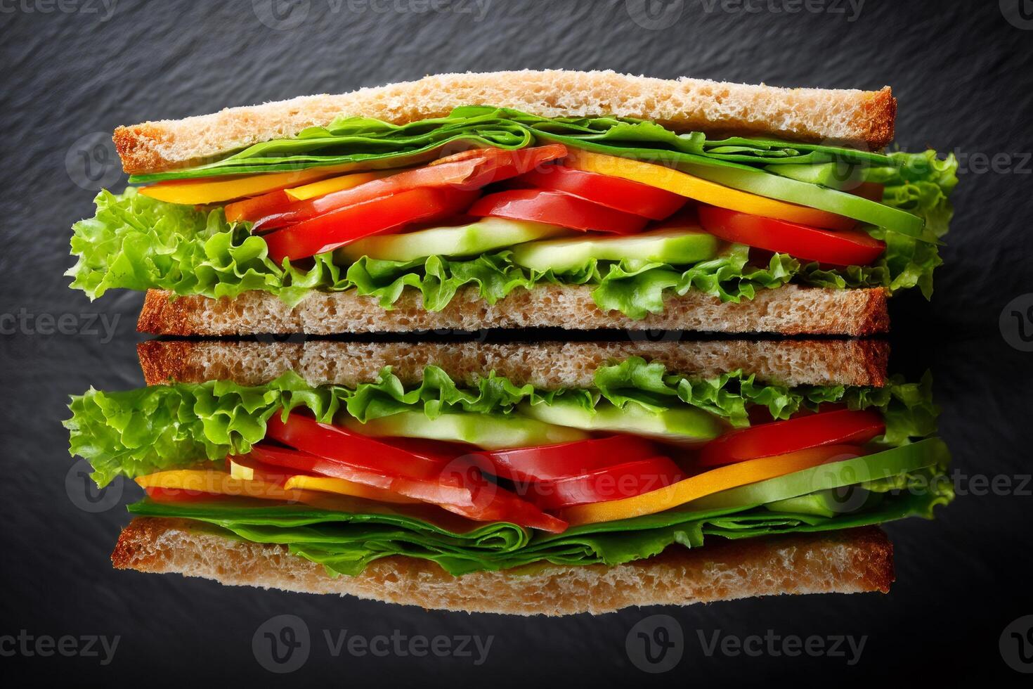 Whole wheat vegan sandwich with lettuce, tomato, cucumber, yellow bell pepper reflecting on a dark background photo