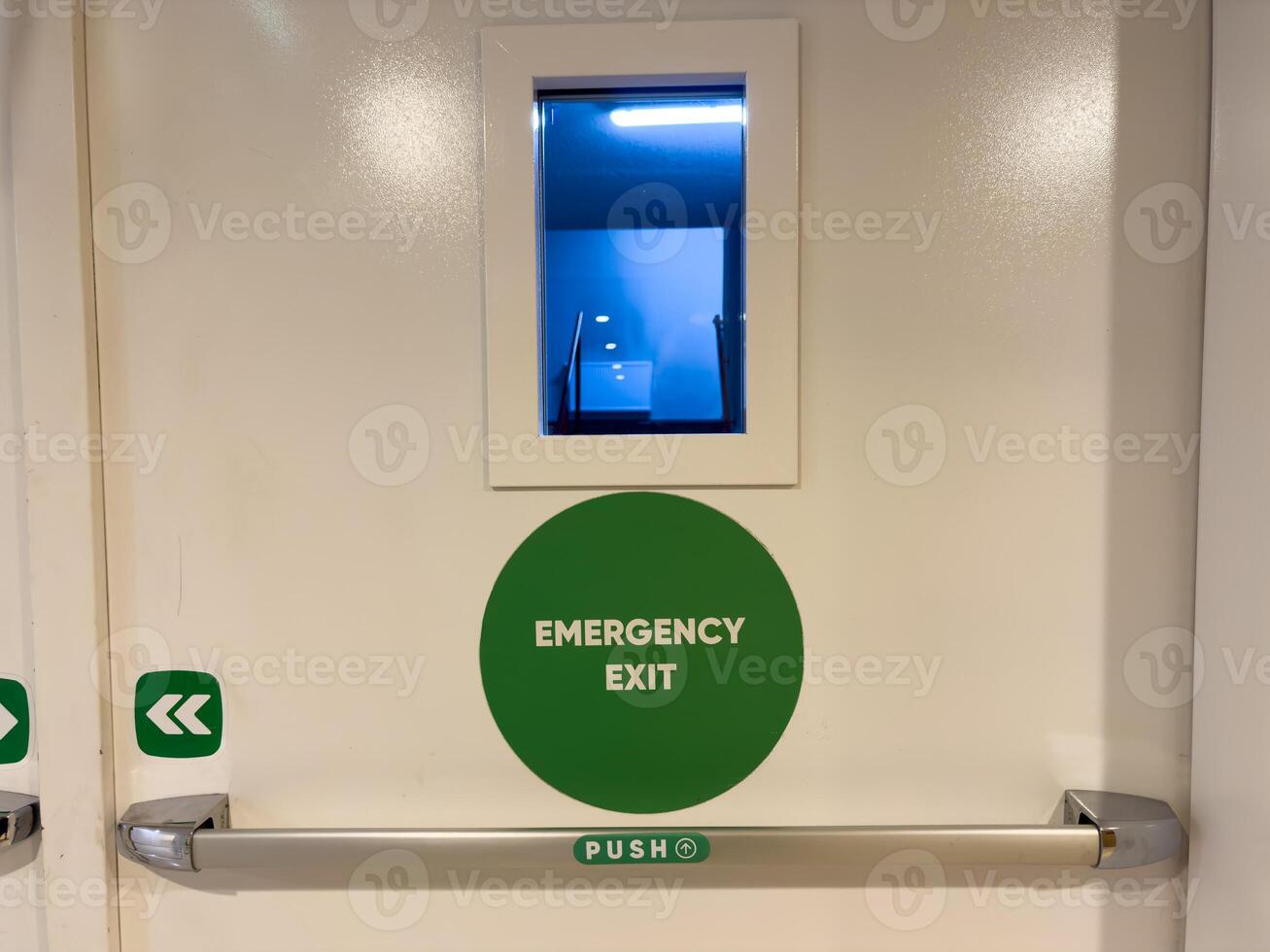 Green emergency fire exit sign or fire escape on ceiling for doorway or door exit in the building for evacuation in the event of a fire and safety prevent or prevention and rescue. photo