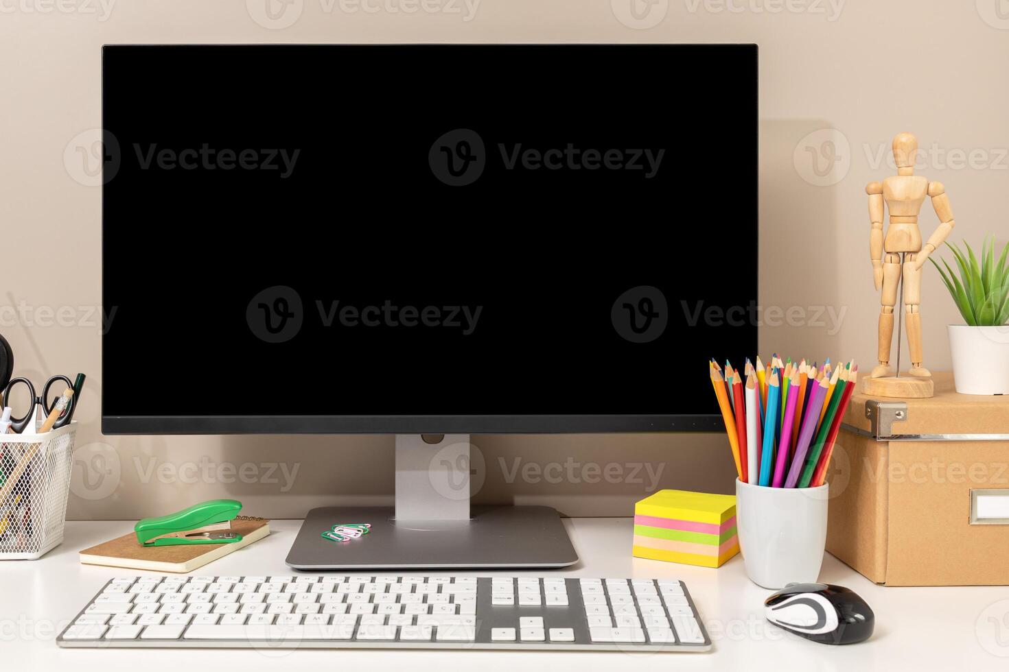 Workspace showing computer with black blank screen, keyboard, mouse and various stationery items, ideal for designers, students or creative workers. Template mockup photo