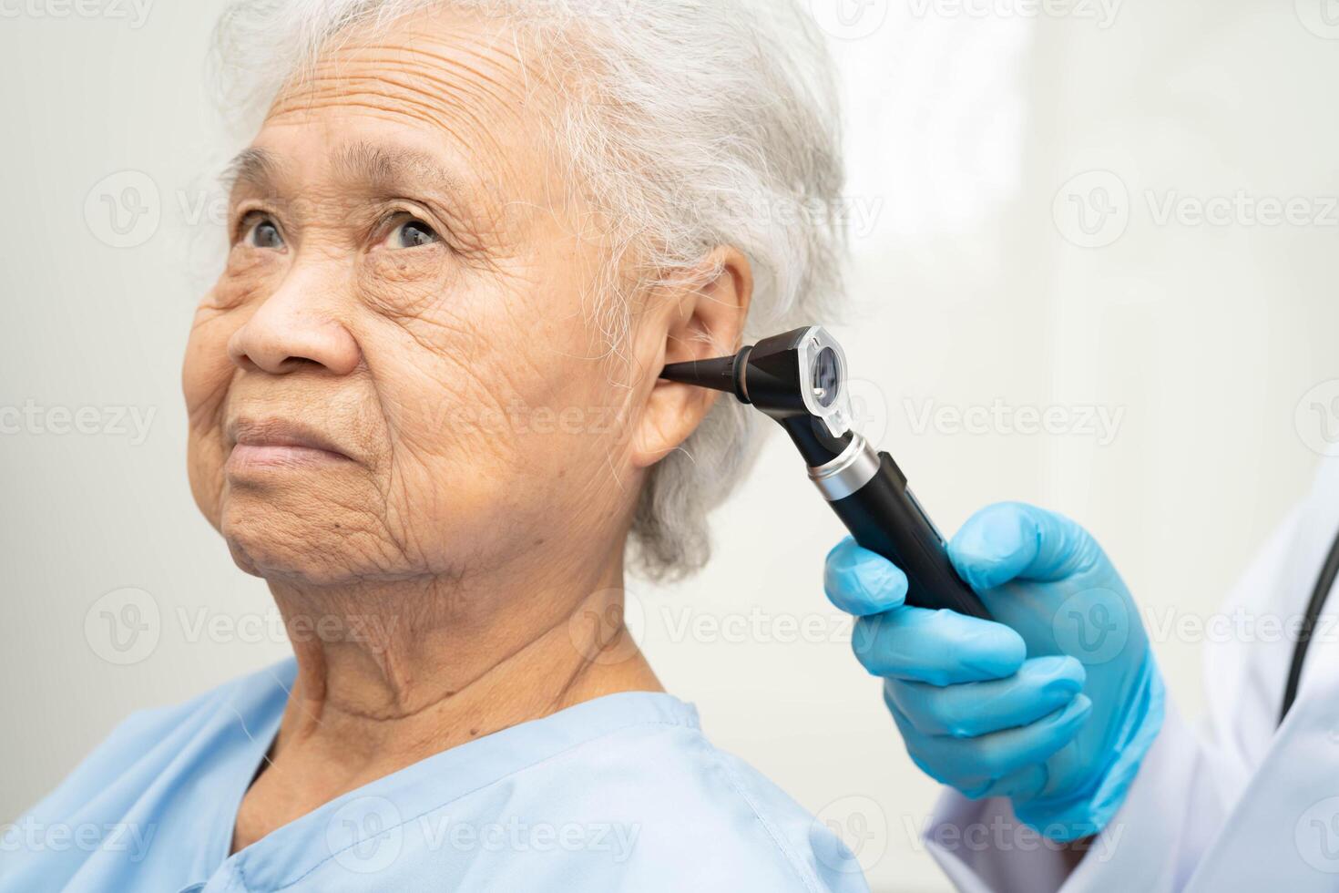 Otolaryngologist ENT physician doctor examining senior patient ear with otoscope, hearing loss problem. photo