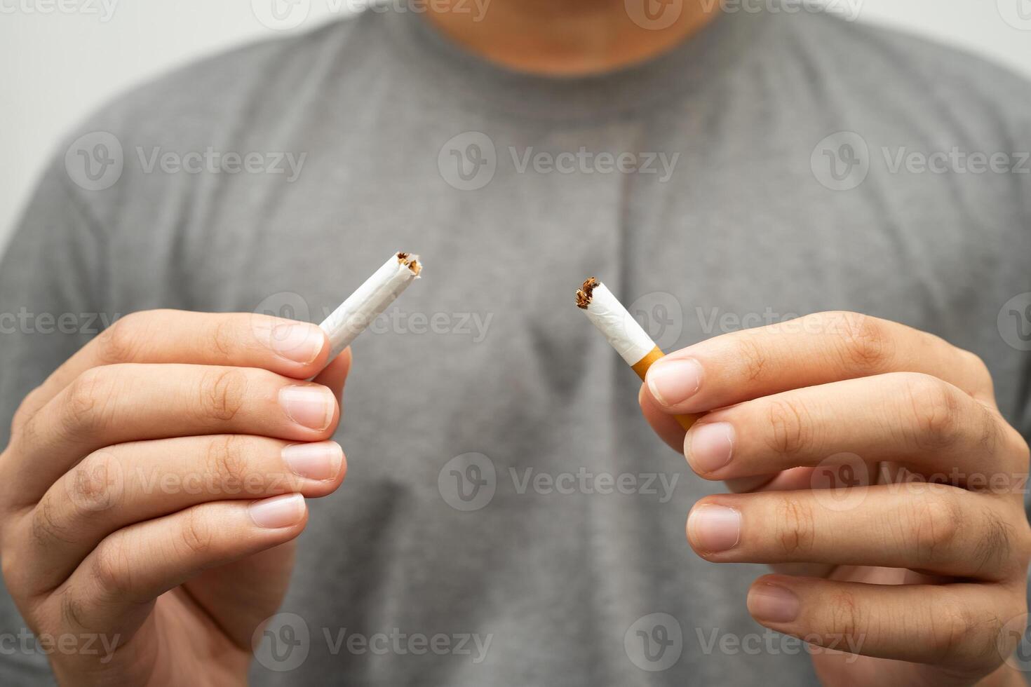 Quit smoking teenage man breaking destroy cigarette in hand. photo