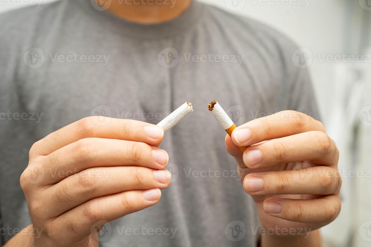 Quit smoking Asian teenage man breaking destroy cigarette in hand. photo