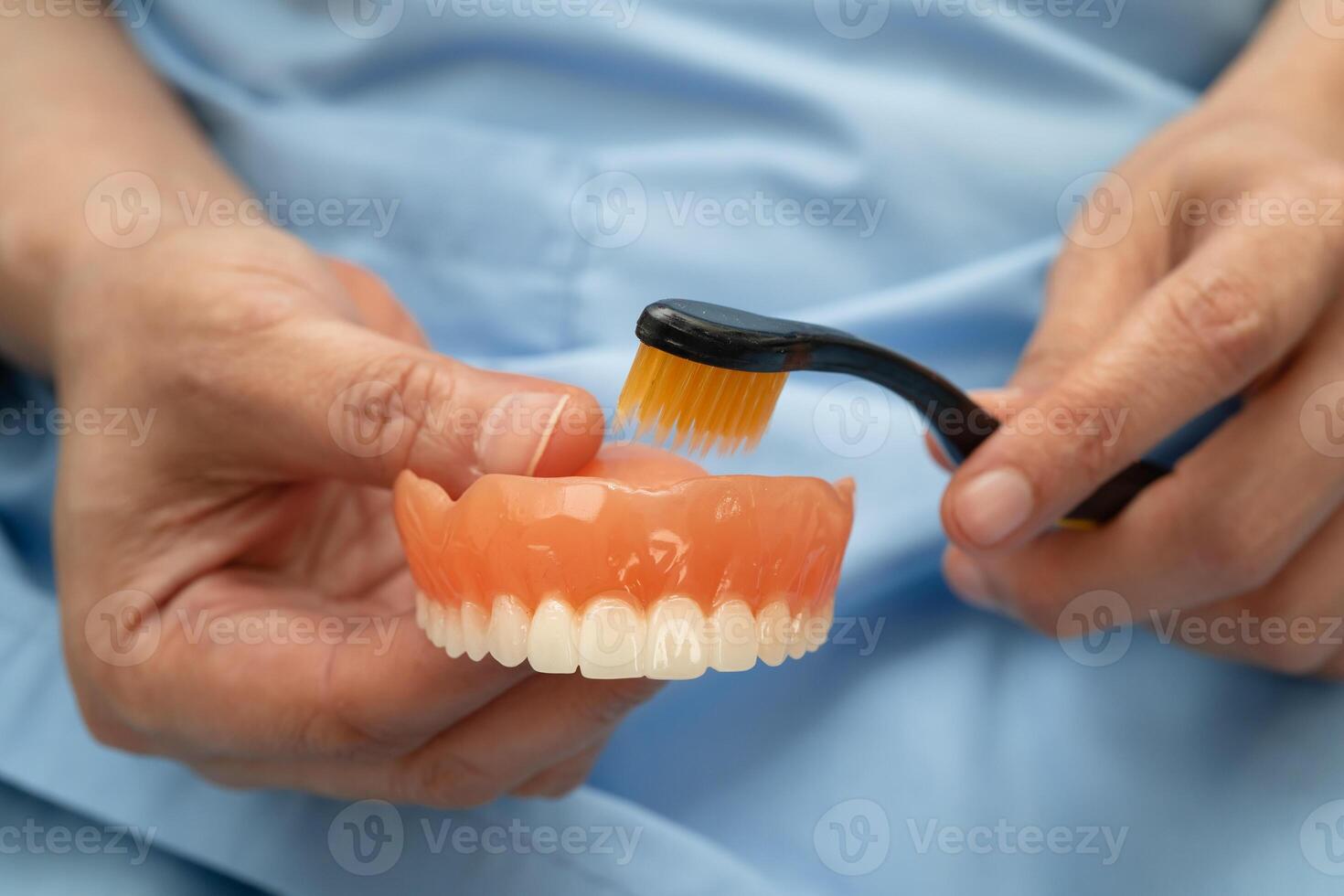 Asian senior woman patient clean teeth denture with toothbrush for chew food. photo