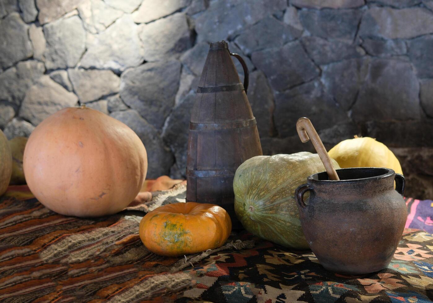 pumpkins and a clay pot, on a bench covered with a hand-woven carpet photo