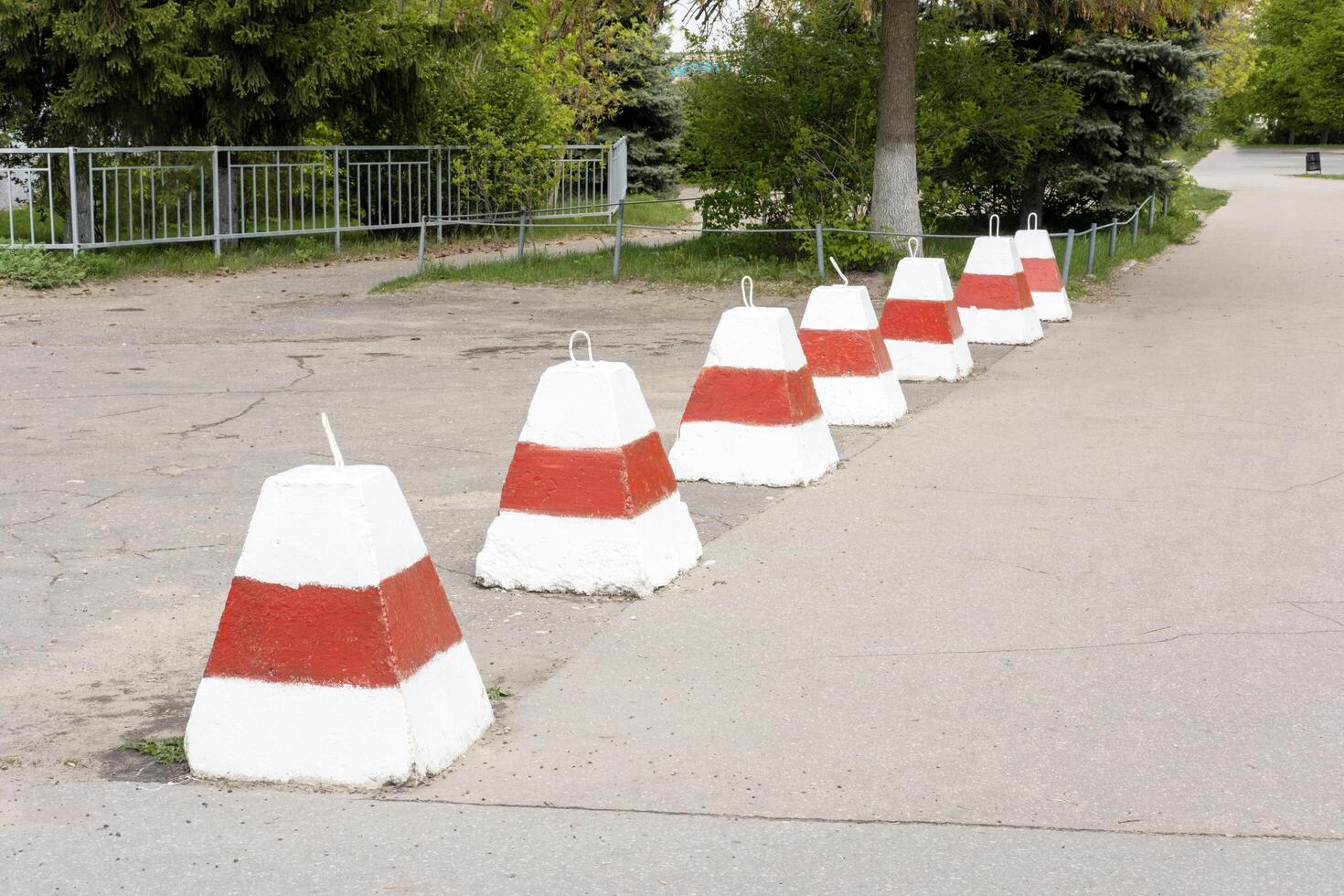 concrete barriers painted in white and red stripes stand on the sidewalk, restricting the movement of vehicles photo