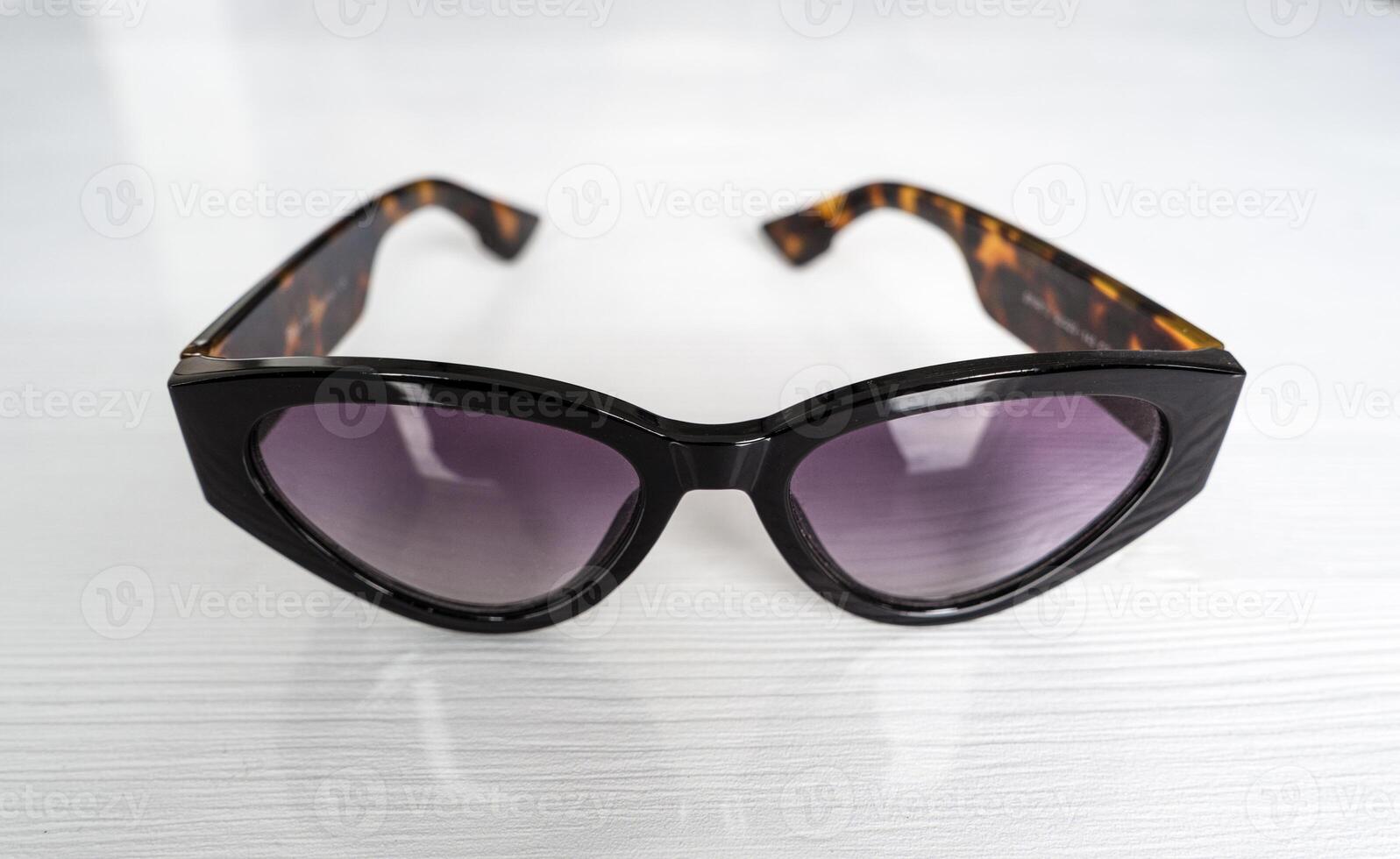 sunglasses with purple lenses on white table photo