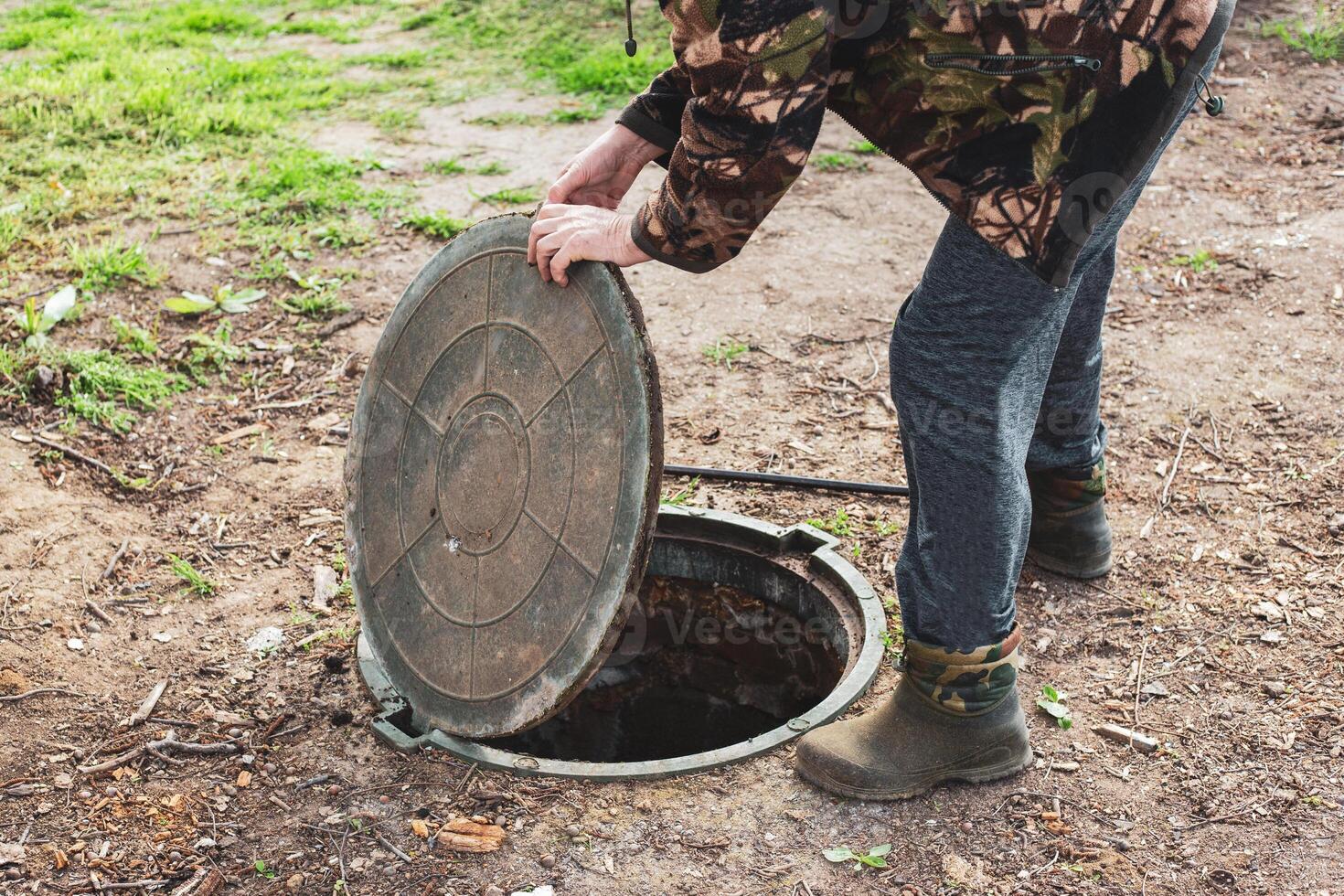 A man opened the septic tank hatch to check the sewer drain level. Septic tanks in a country house. photo