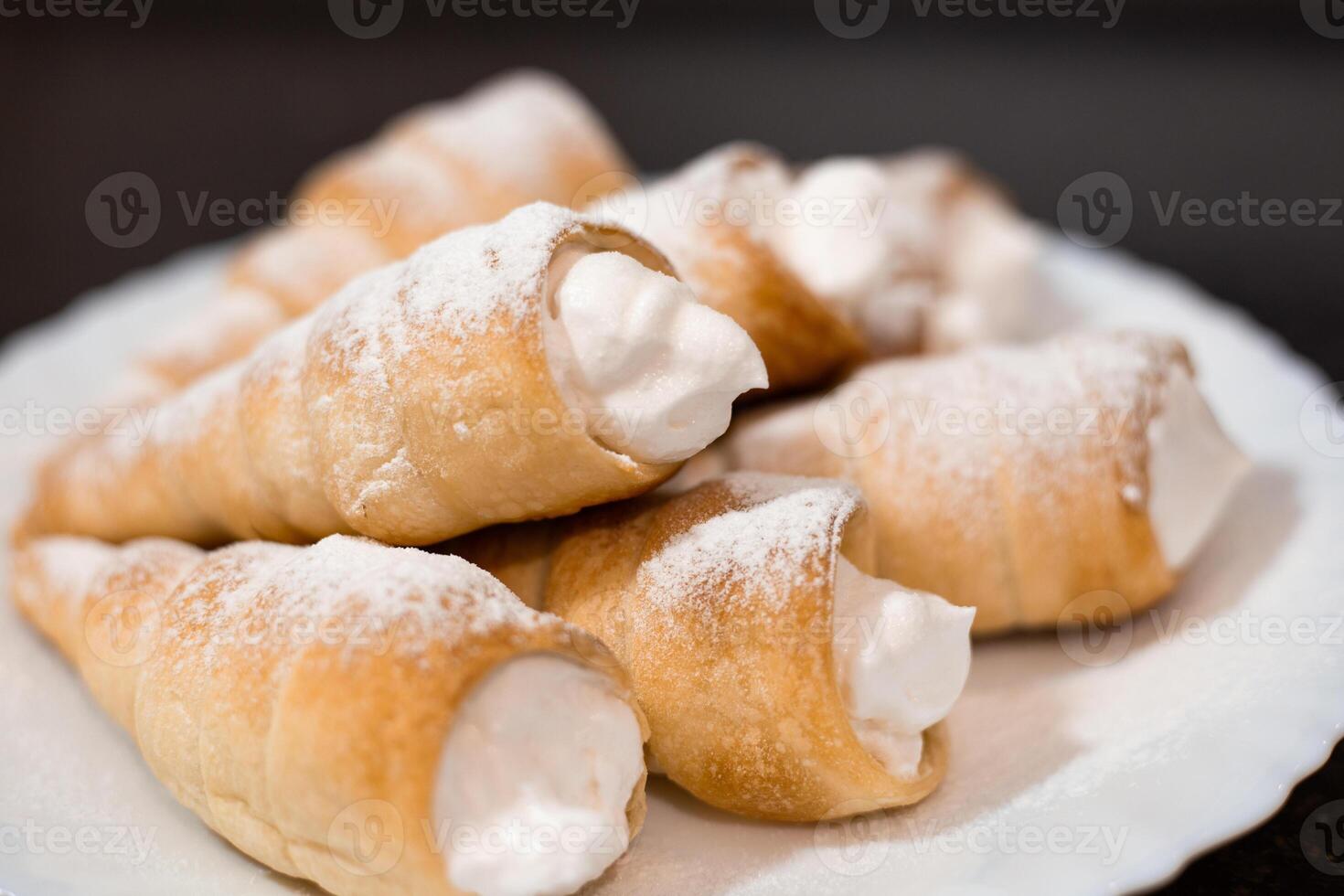 Fragrant puff pastry tubes with protein cream on a white plate. Preparation of sweet pastries, close-up photo