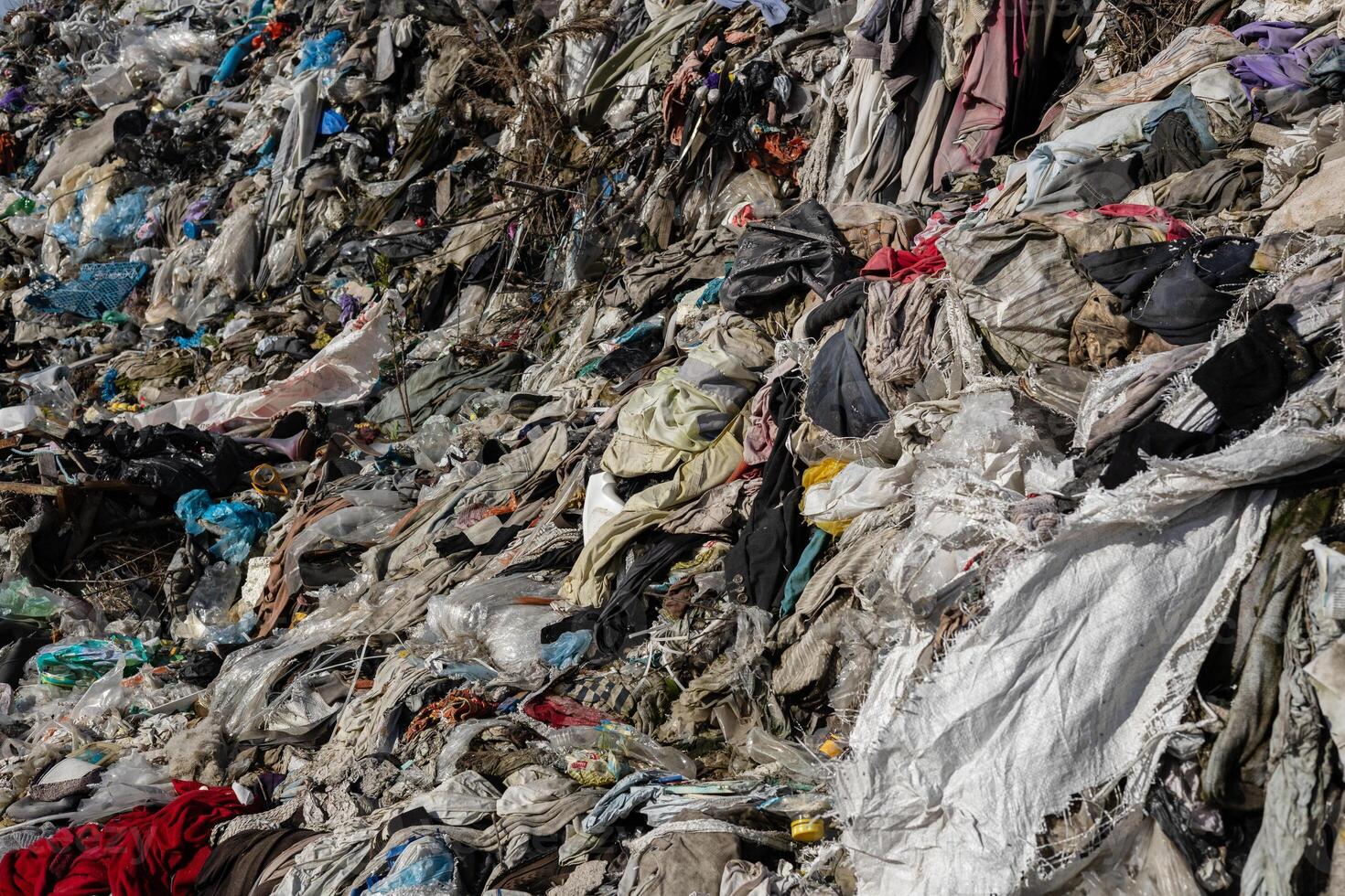 Textiles and clothing are strewn across a landfill, highlighting the issues of waste management and pollution in urban environments photo