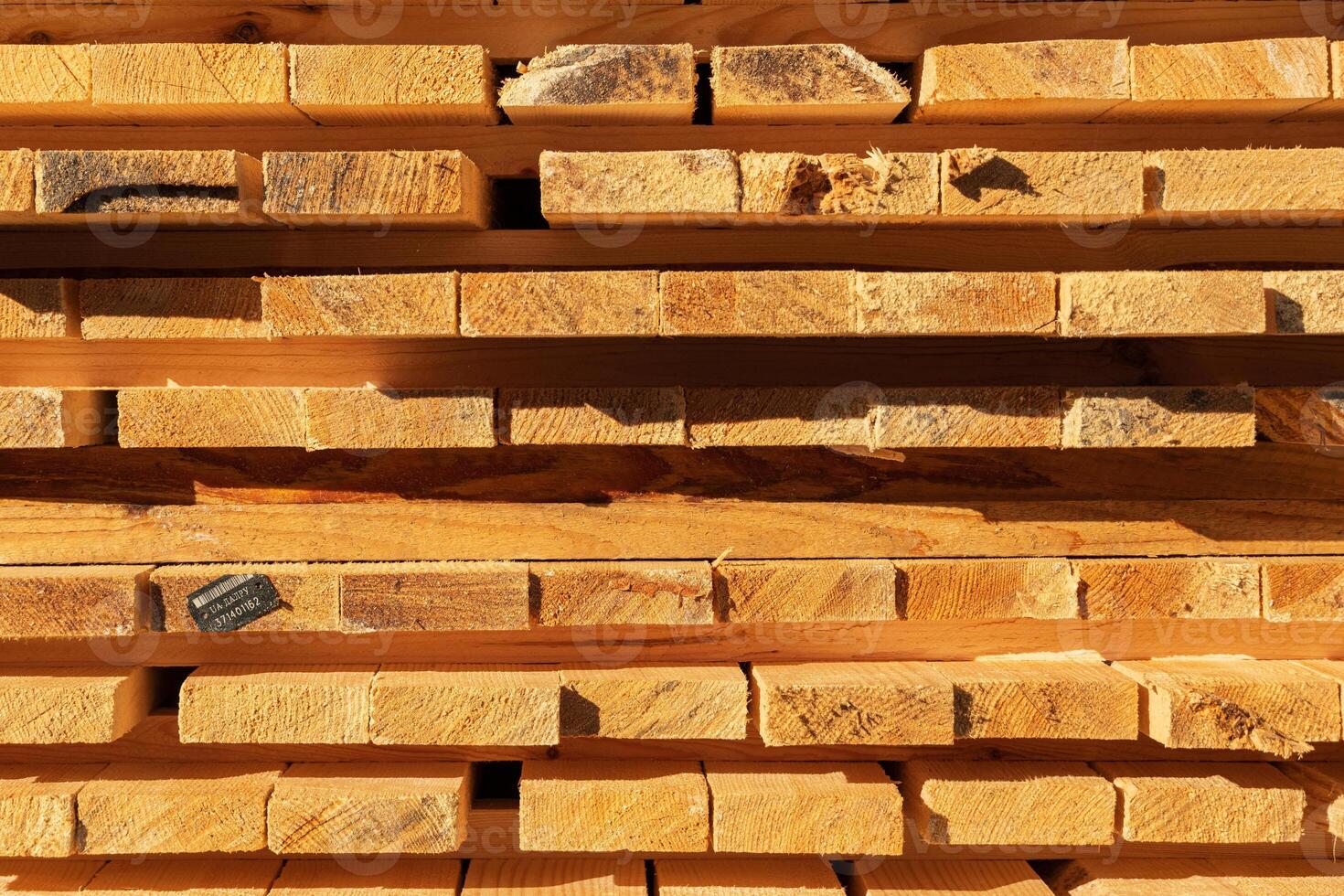 Sunlight illuminates neatly stacked wooden planks at a construction site, showcasing their natural texture and color variations photo