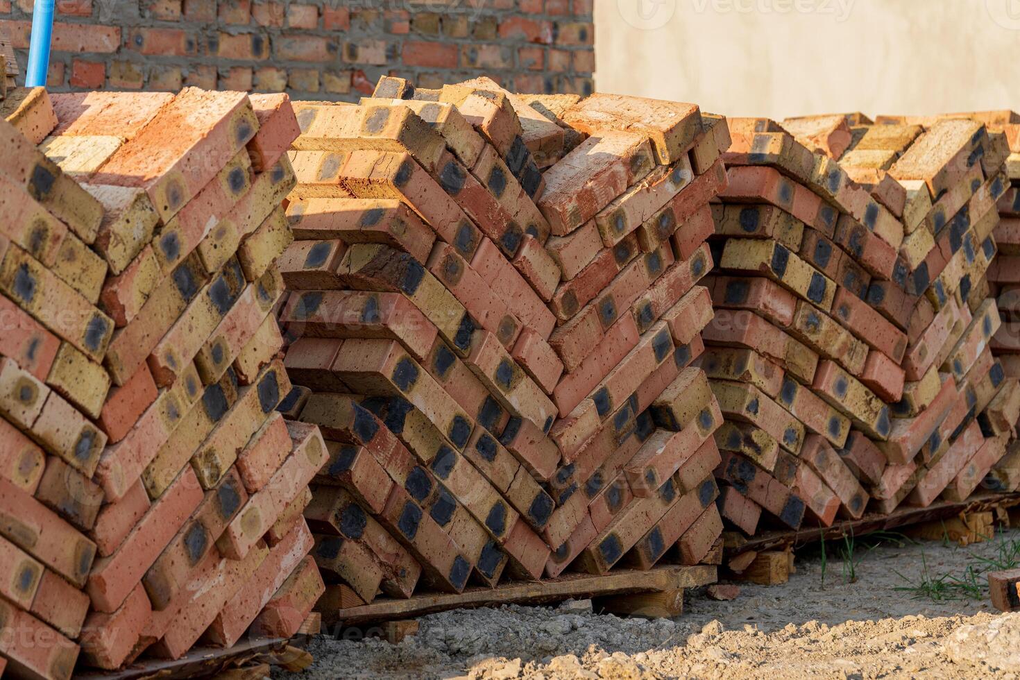 Neatly stacked bricks are arranged on wooden pallets at a construction site under bright sunlight during the afternoon hours photo