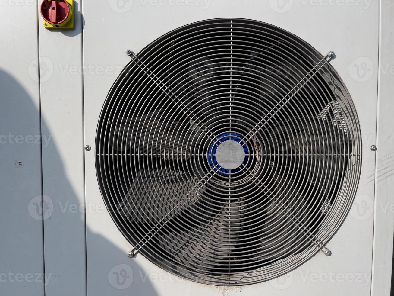 Cooling fan spins steadily on outdoor HVAC unit, providing essential climate control during hot summer day in city environment photo