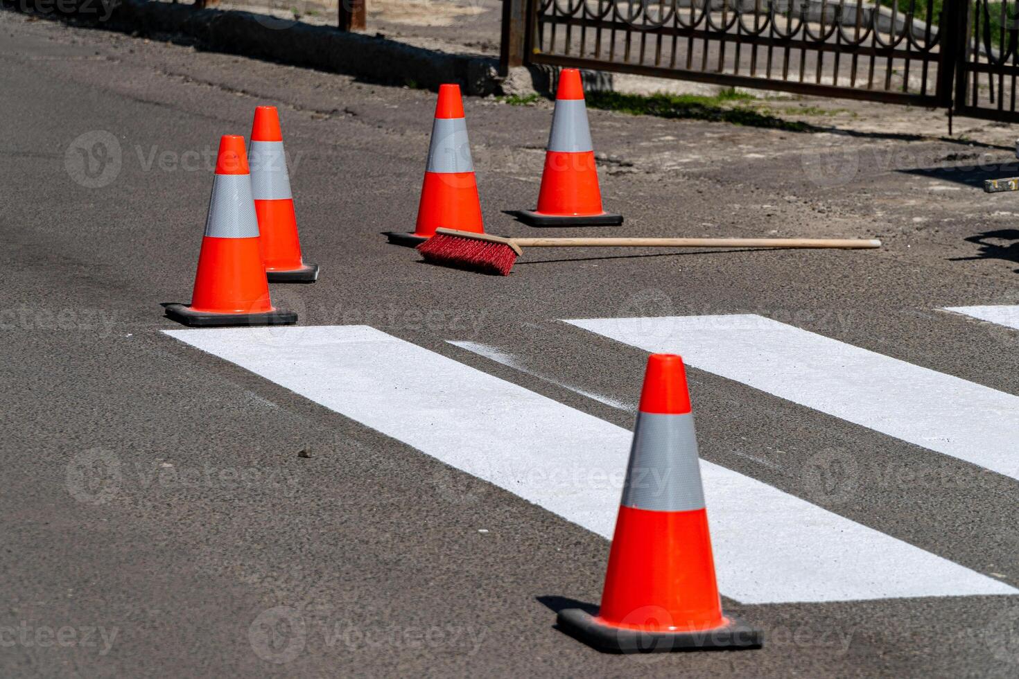 Traffic cones surround a freshly painted pedestrian crossing in a busy urban street during daytime, ensuring safety during repainting photo