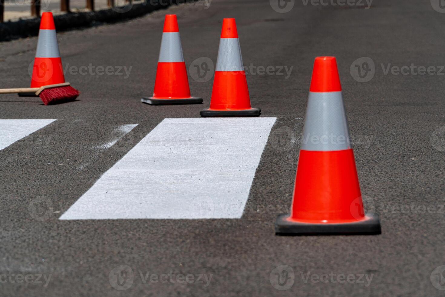 Traffic cones block a fresh zebra crossing marking on a city street during road maintenance in bright sunlight photo