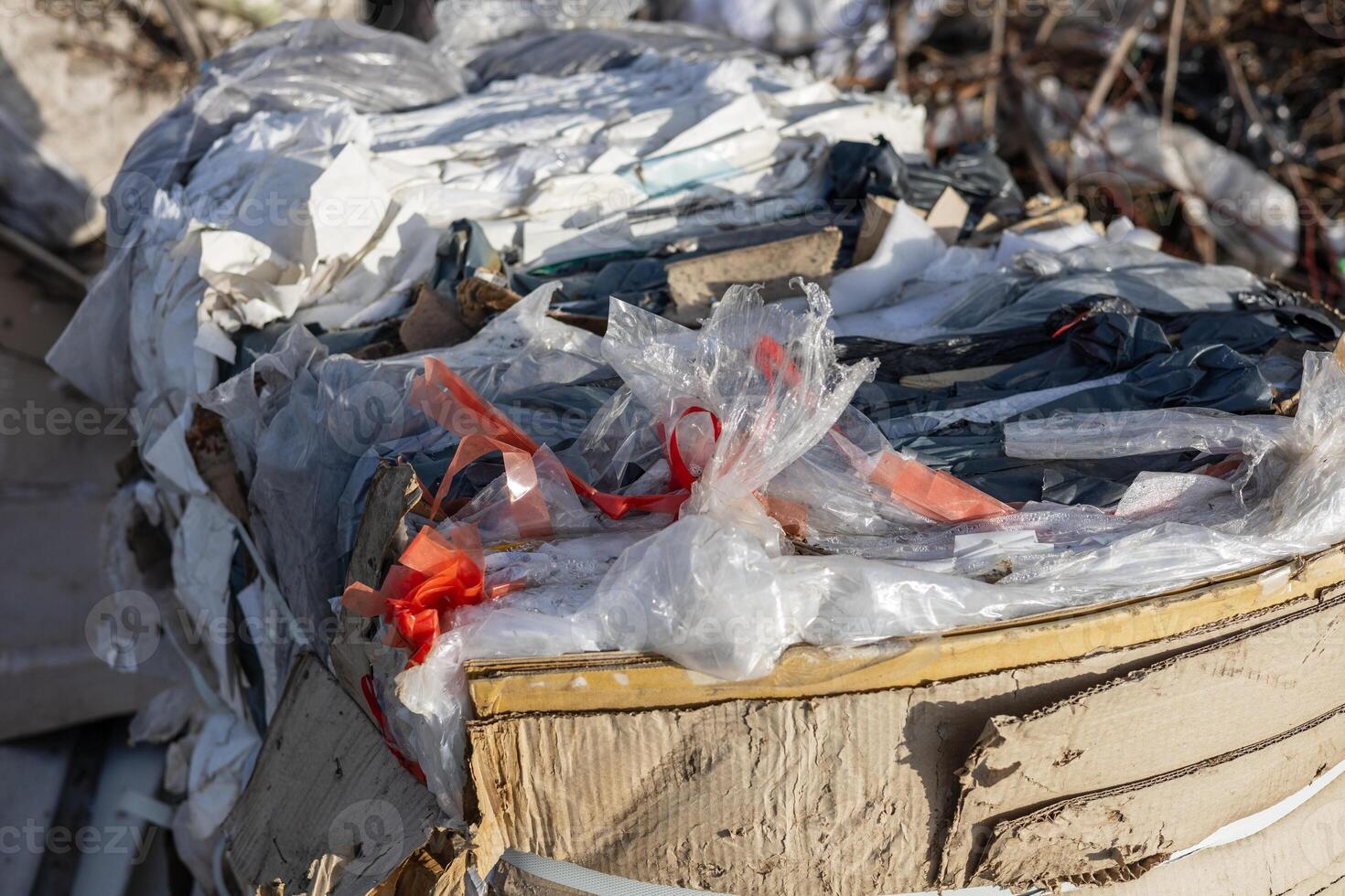 Piles of plastic, cardboard, and mixed debris are stacked high in a junkyard, showcasing the effects of urban waste accumulation photo