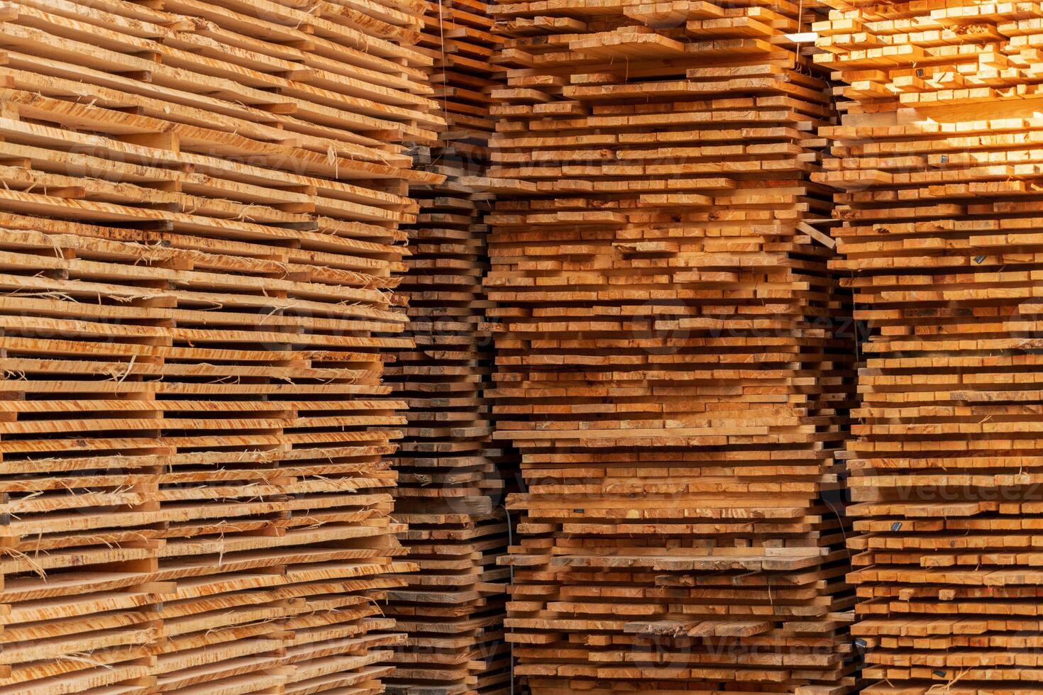 Lumber stacked neatly in a yard, showing different types and sizes of wooden planks under natural light. The warm tones enhance the texture photo