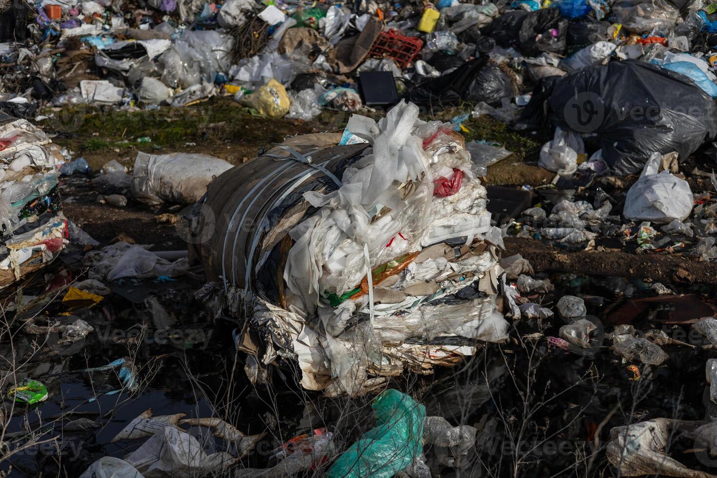 A large pile of waste materials dominates the landscape, highlighting serious issues of pollution and waste management in urban environments photo