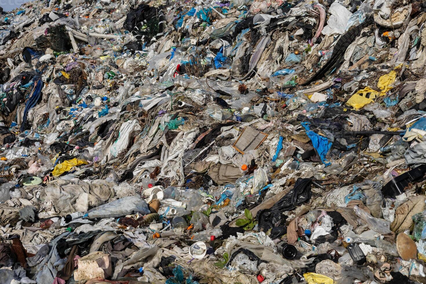 A vast pile of mixed waste is visible, showcasing discarded textiles, plastics, and debris. This landfill reflects ongoing environmental challenges photo