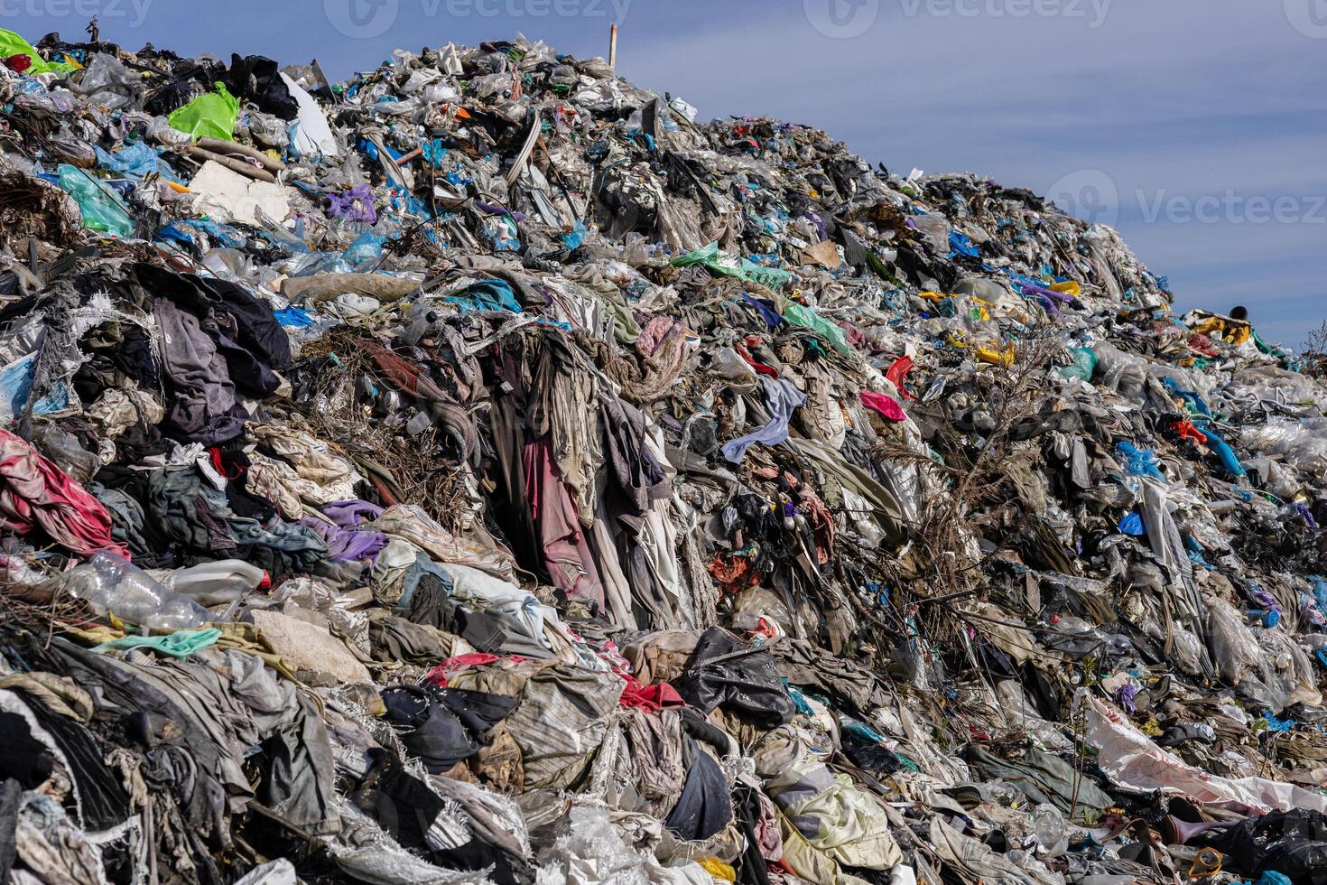 Numerous layers of garbage and discarded materials stack up at a landfill, showcasing the heavy pollution and environmental impact photo