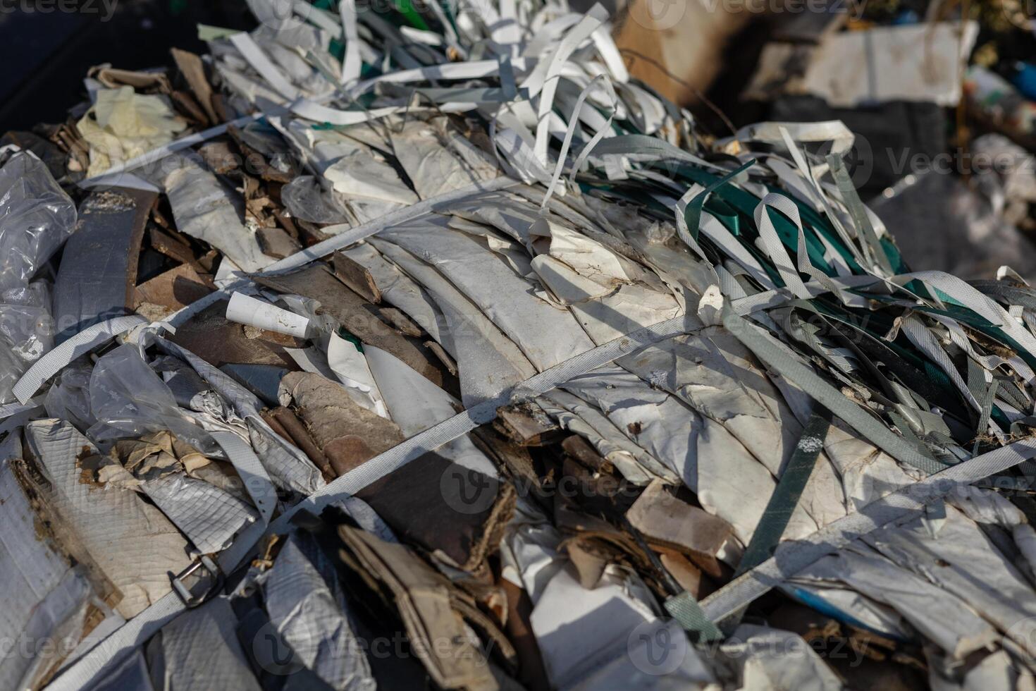 Compacted waste materials are securely bound with straps at a landfill site, highlighting the challenges of pollution and waste management photo