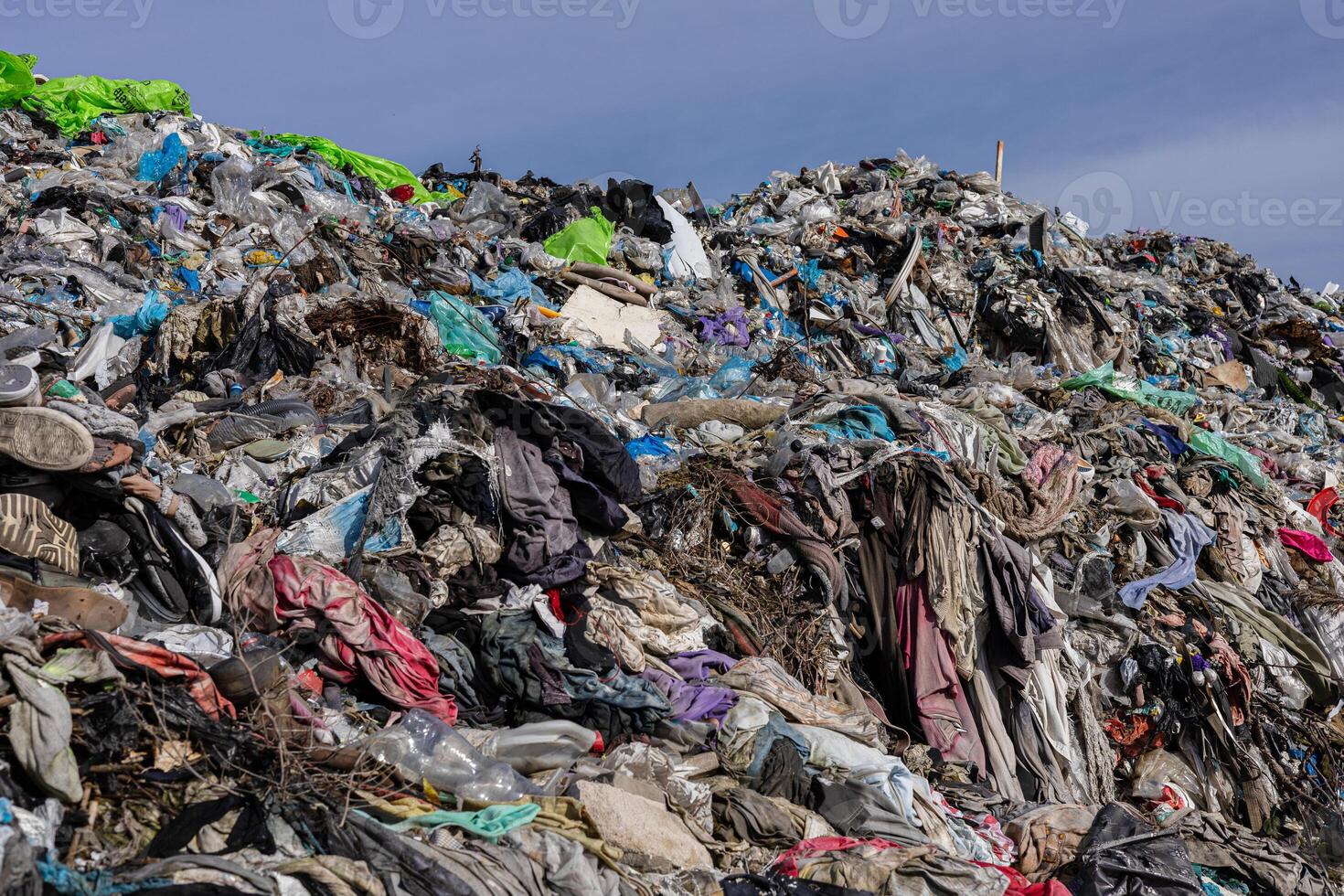 A vast accumulation of discarded clothing, plastic, and debris fills the landfill, highlighting urgent issues of pollution and waste management photo