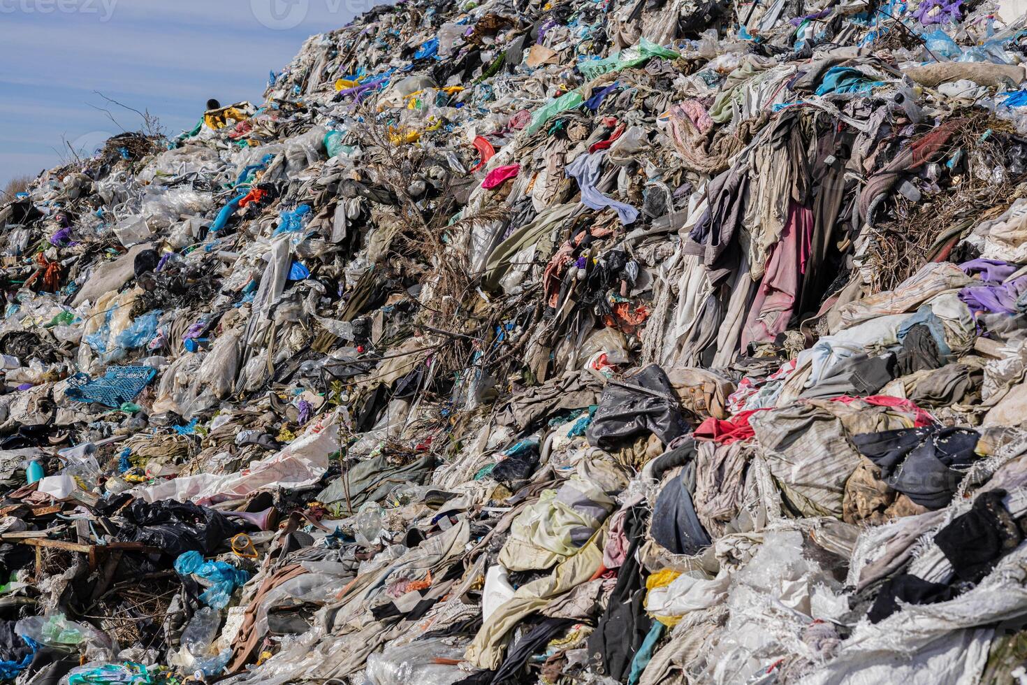 A vast landfill stacked with clothes, plastic, and trash underscores urgent pollution issues and the need for recycling photo