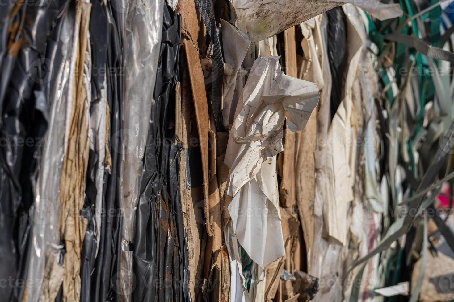 Layers of various recyclable materials are stacked together in a facility during the day, showcasing different textures and colors photo