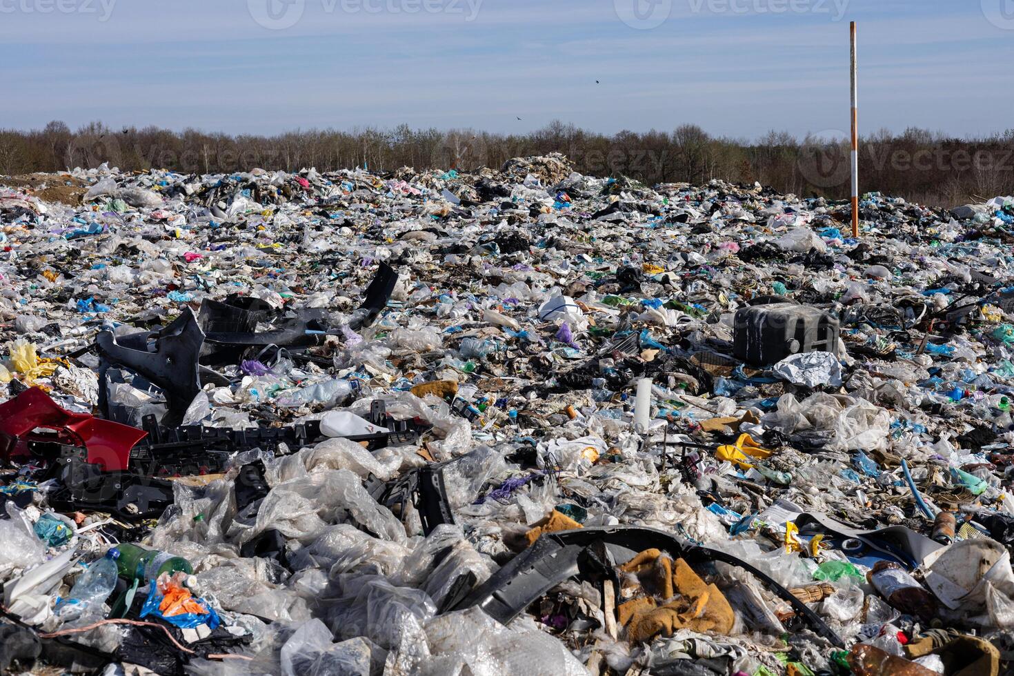 Large area filled with various types of plastic waste and garbage under a clear blue sky, highlighting environmental impact and pollution photo