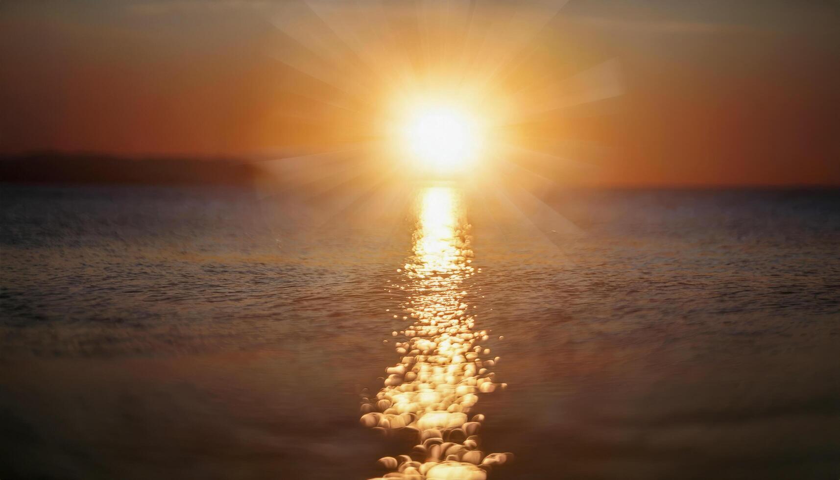 A glowing sunrise over a peaceful sea, golden light shimmering on the surface, symbolizing warmth and solar energy. photo