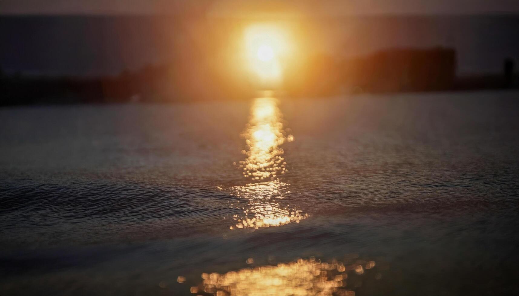 A glowing sun rising over a calm ocean, with golden light photo
