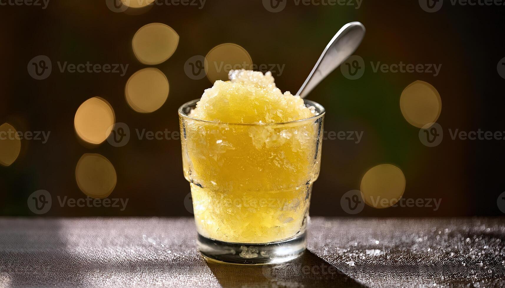 Refreshing lemon granita dessert in glass with spoon and bokeh lights on background. photo