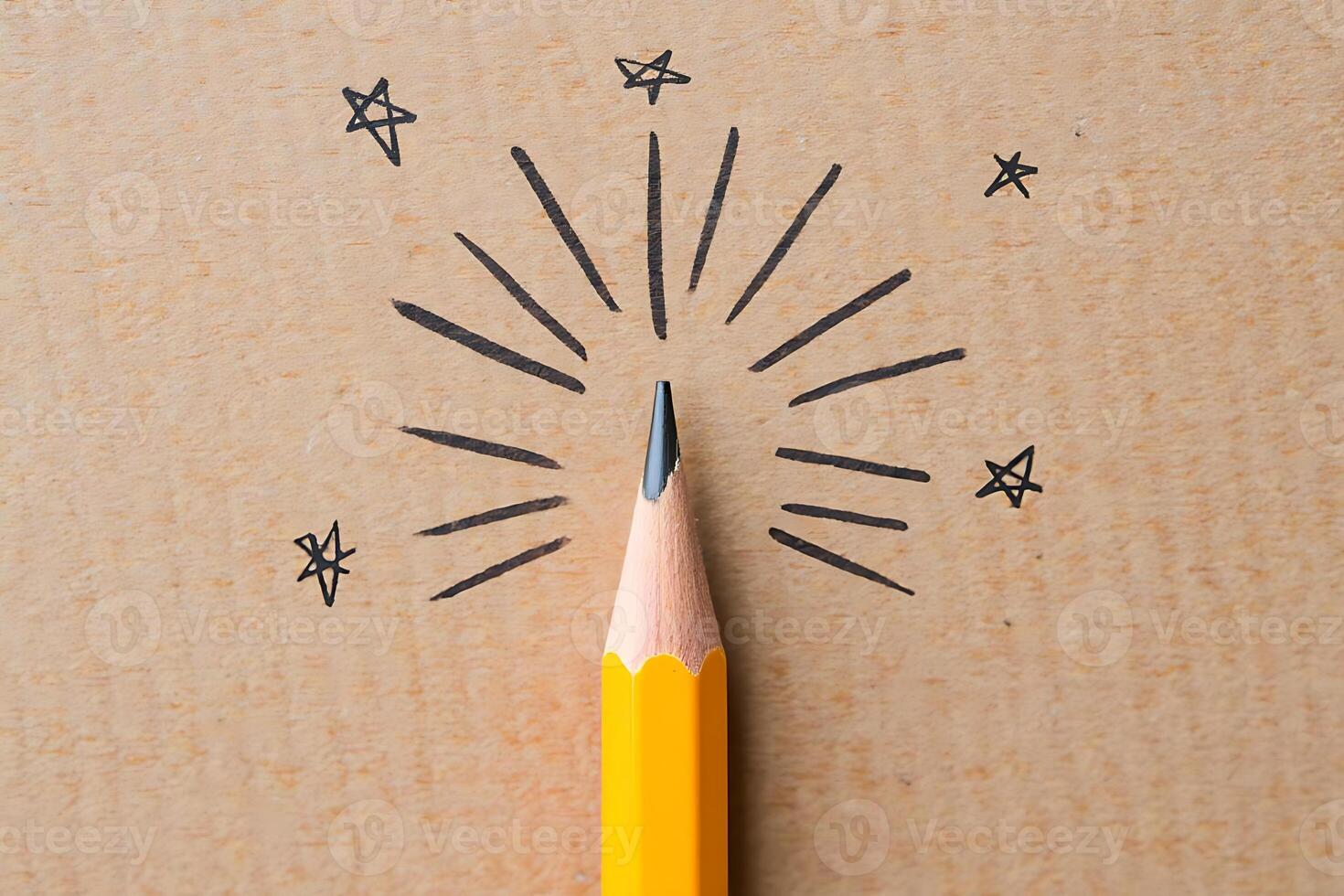A yellow pencil point with lines and star symbols demonstrating creativity and education concept on a wooden surface photo