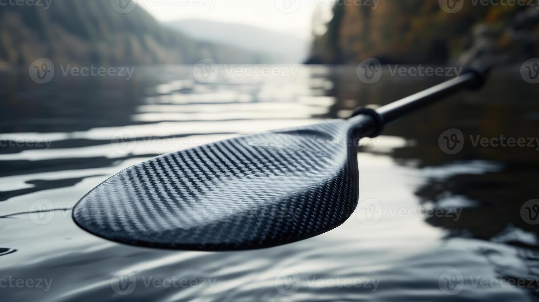 Close-up view of a carbon fiber kayak paddle in water. photo