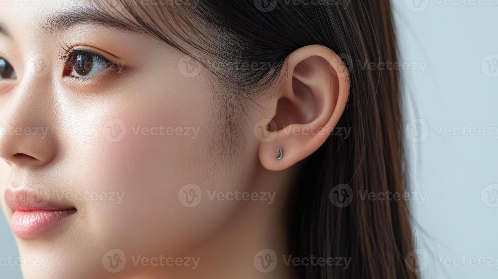 Close-up profile view of a woman's face and earlobe with small studs. photo